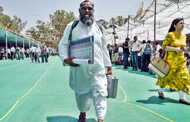 An election official leaves after collecting an Electronic Voting Machine (EVMs) from a polling materials distribution centre in Haridwar on April 18, 2024, on the eve of phase one of India's general election.