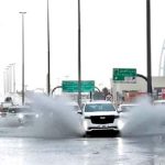 An SUV splashes through standing water on a road with the Burj Al Arab luxury hotel seen in the background in Dubai, United Arab Emirates, April 16, 2024.