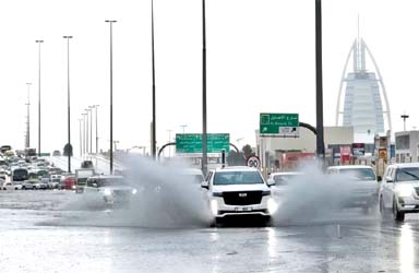 An SUV splashes through standing water on a road with the Burj Al Arab luxury hotel seen in the background in Dubai, United Arab Emirates, April 16, 2024.