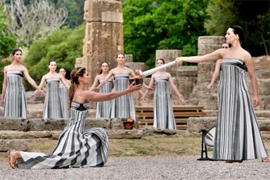 Actress Mary Mina, playing high priestess, right, lights a torch during the official ceremony of the flame lighting for the Paris Olympics, at the Ancient Olympia site, Greece, on April 16, 2024.