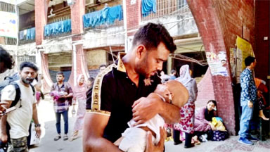 The image shows a man holding a baby after the fire broke out at the Bangladesh Shishu Hospital in Dhaka on Friday, April 19, 2024.