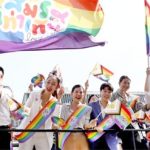 Members of the LGBTQ+ community hold flags that read "Marriage equality, love”.