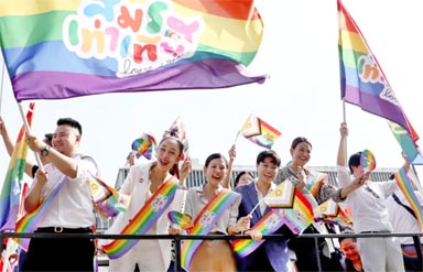 Members of the LGBTQ+ community hold flags that read "Marriage equality, love”.